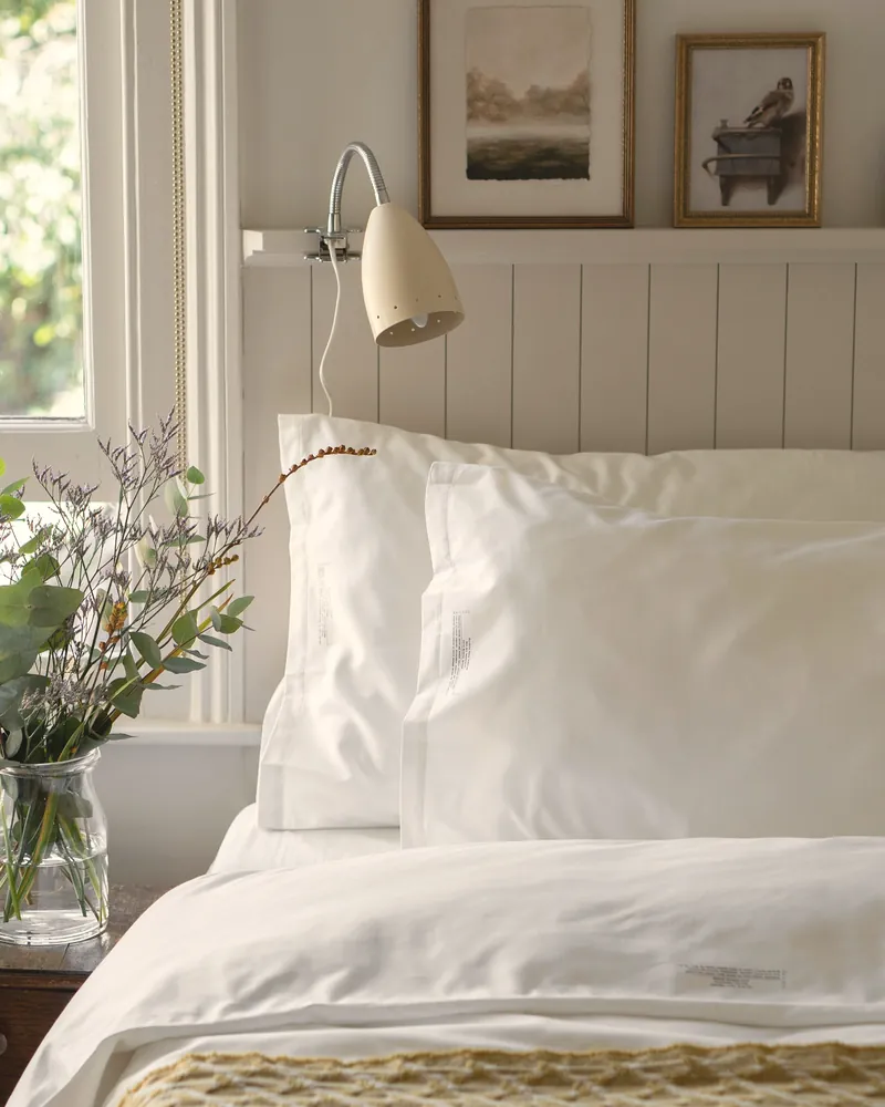 Lit fait, oreillers blancs, lumière du matin
